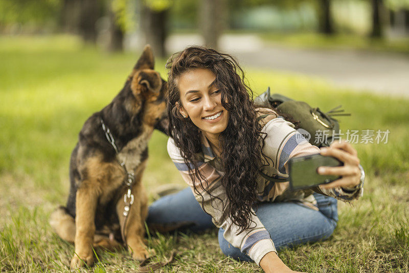 一个女人和她的狗在用手机自拍