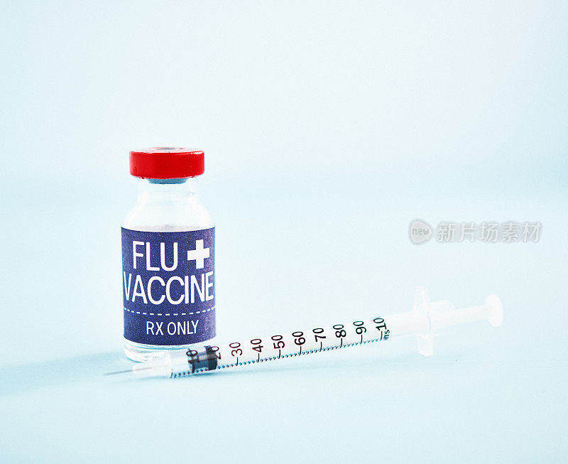 亮蓝色背景上带注射器的流感疫苗小瓶