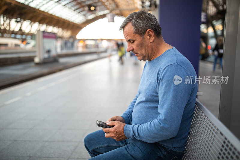 一名男子在火车站等车时使用手机