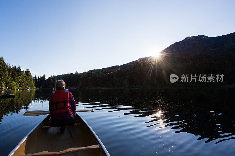 在山上的湖上划独木舟的女人