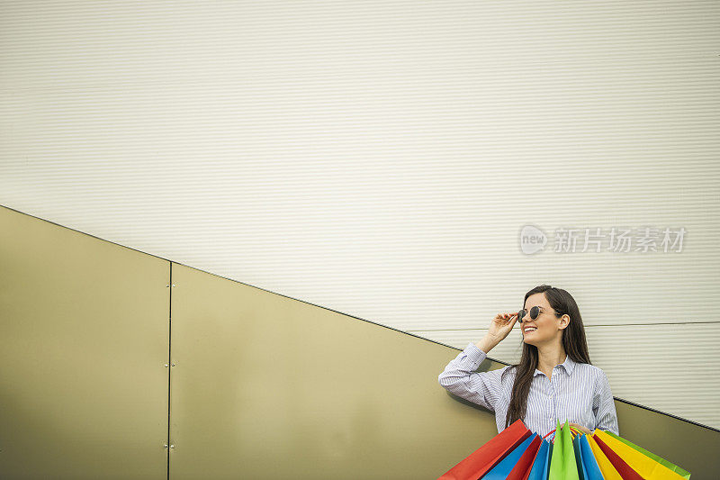 年轻快乐的女人愉快地微笑着她的购物袋孤立在灰色背景与副本空间