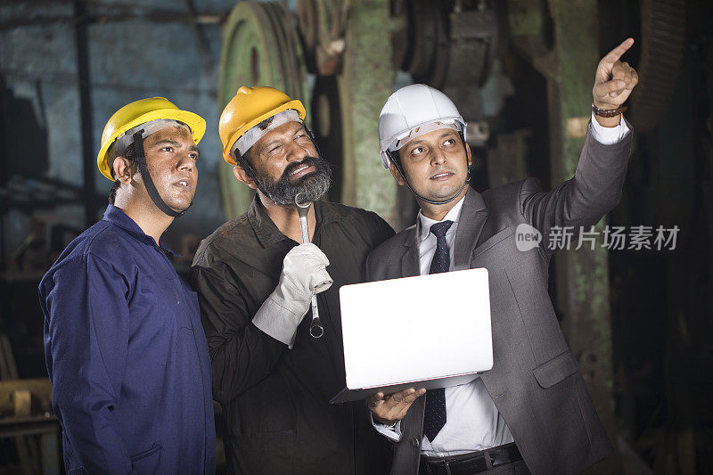 机械师与工程师在工厂使用笔记本电脑进行讨论