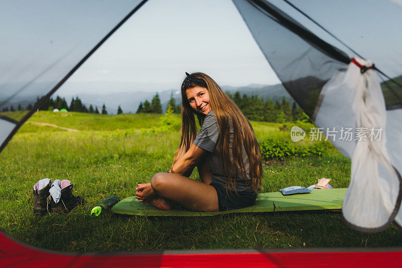 一个年轻女子在山里露营时遇到了一个明亮的夏日早晨