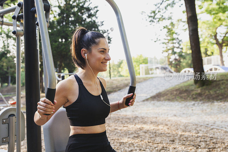 年轻的运动女性在户外健身房锻炼