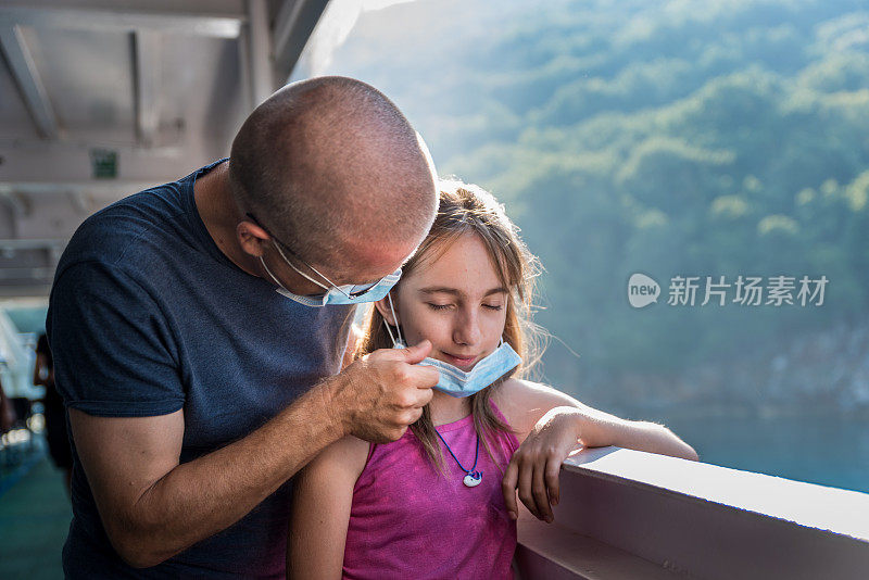 父亲和女儿去度假乘渡船旅行，并戴着防护口罩