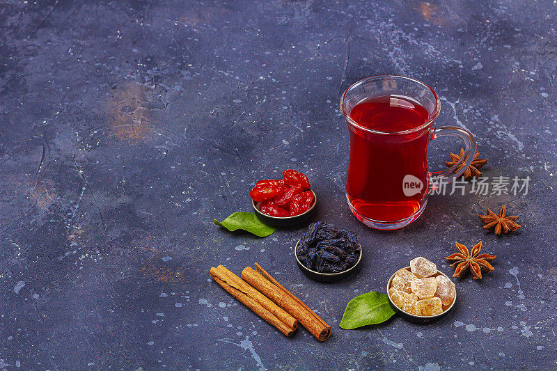 在土耳其茶杯(armudu)中加入东方风格的山茱萸、葡萄干和糖，在深色背景上饮用红茶(rooibos，芙蓉，karkade)。草药，维他命，排毒茶治疗感冒和流感。文本复制空间