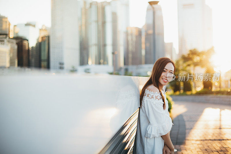 亚洲年轻开朗的女人在美丽的夕阳下看着相机