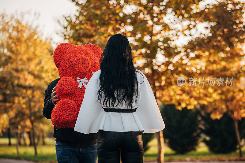 一个年轻人在户外用泰迪熊给女朋友一个惊喜