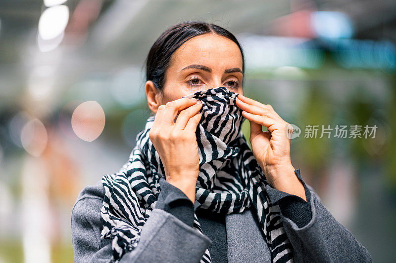 在冠状病毒大流行期间，一名妇女调整她的黑白围巾作为替代面部遮盖物