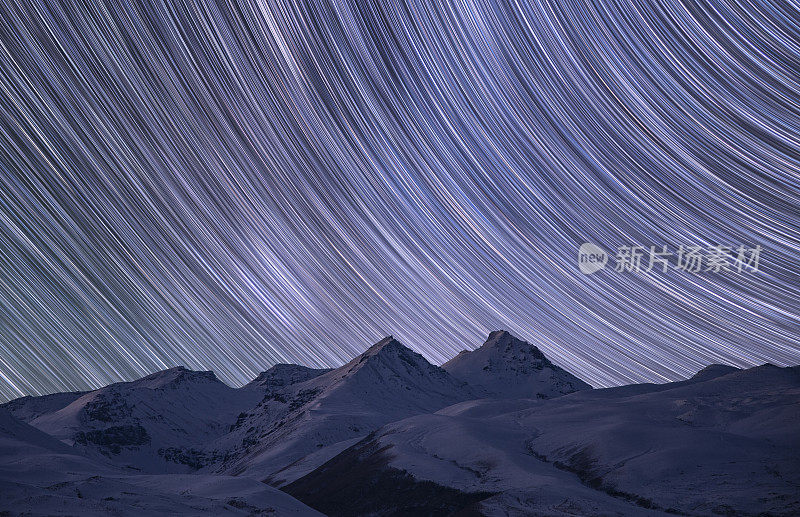 冬夜山水，雪山下五彩缤纷的星空痕迹。夜间延时摄影。