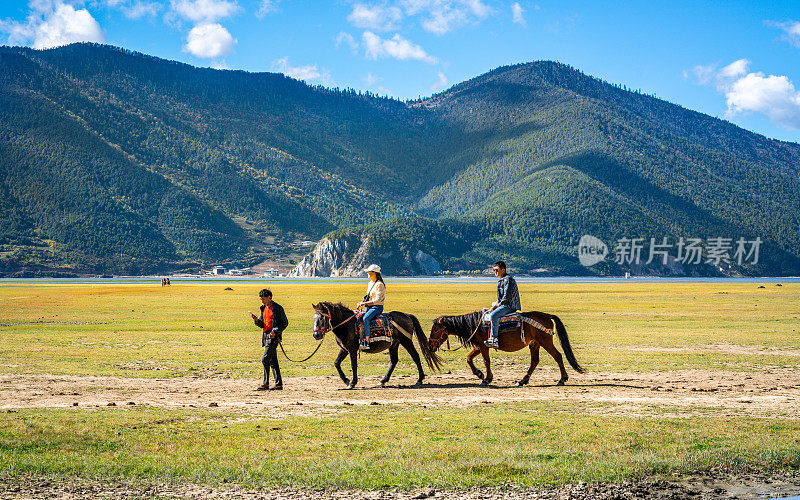 阳光明媚的日子里，两名中国游客在云南香格里拉的纳帕海草原自然保护区骑马