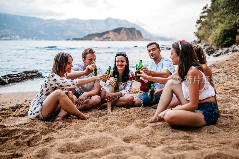 朋友们在海滩上玩吉他，喝啤酒
