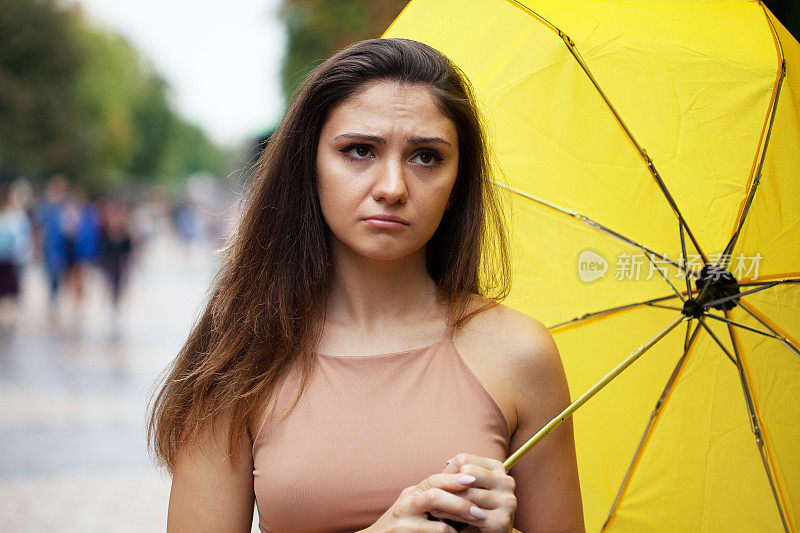 沮丧的年轻女子打着伞