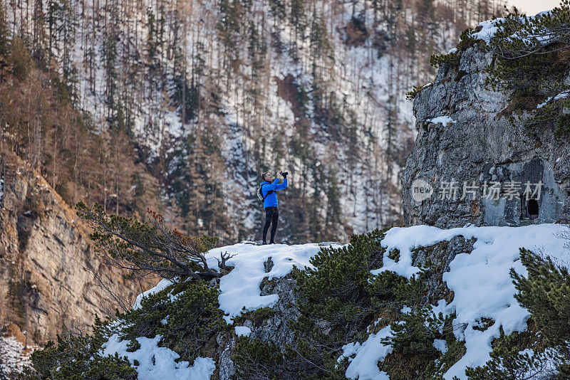 冬天，一名白人跑步者在山顶停下来