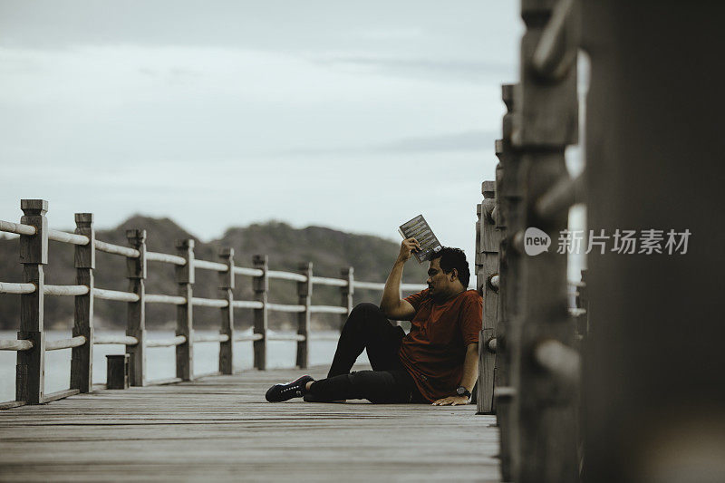 亚洲人在木桥上看书