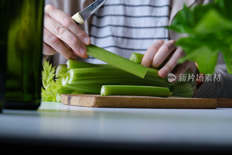 人手正在用生菜、芹菜茎、青苹果、橙子和鳄梨准备生沙拉