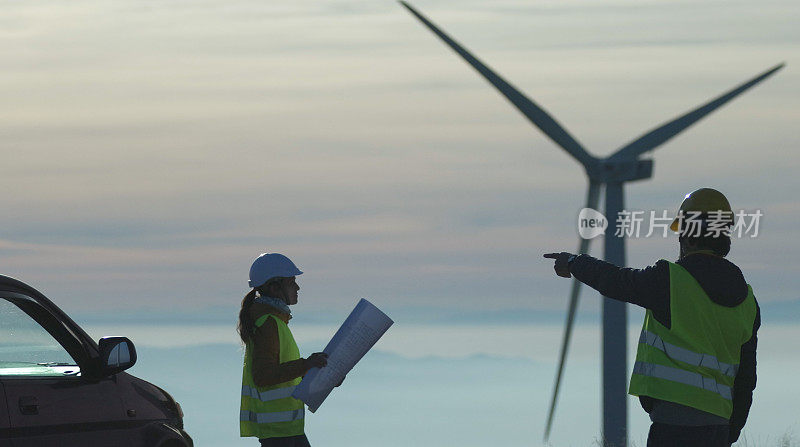 黄昏时分，风能工程师在风电场工作。可再生能源系统。碳中和和可持续能源。