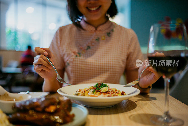 亚洲女人在餐厅吃奶油干酪意面