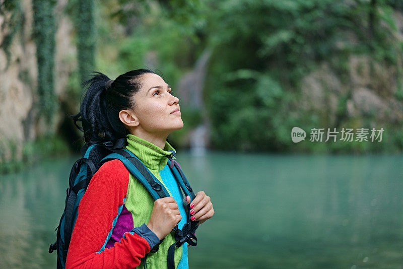 年轻女子在瀑布前呼吸着纯净的空气