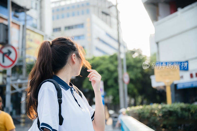 亚洲女孩在一个阳光明媚的日子放学回家