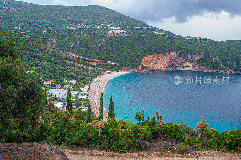 奇特的海滩附近的帕尔加与沙子和鹅卵石海滩和一个大岩石在蓝色的大海，在松树林。地平线和蓝天的背景视图