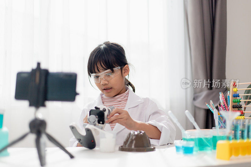 亚洲女学生做简单的化学实验并为他的追随者录制视频，年轻的博主孩子在镜头前为vlog摆姿势，儿童为社交媒体渠道概念制作vlog。