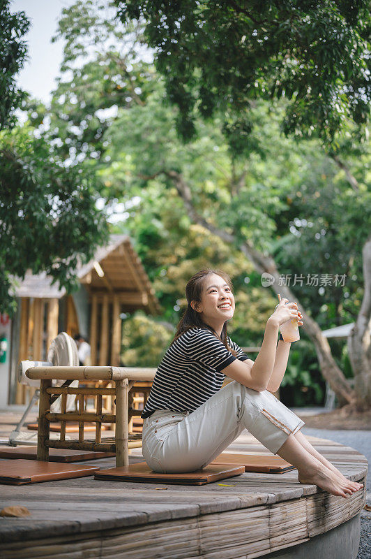 快乐迷人的年轻女子坐在享受自然氛围下的夏季树新鲜空气