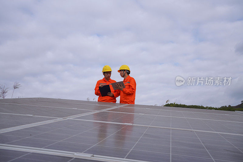 两个亚洲男性工程师在太阳能发电站前讨论