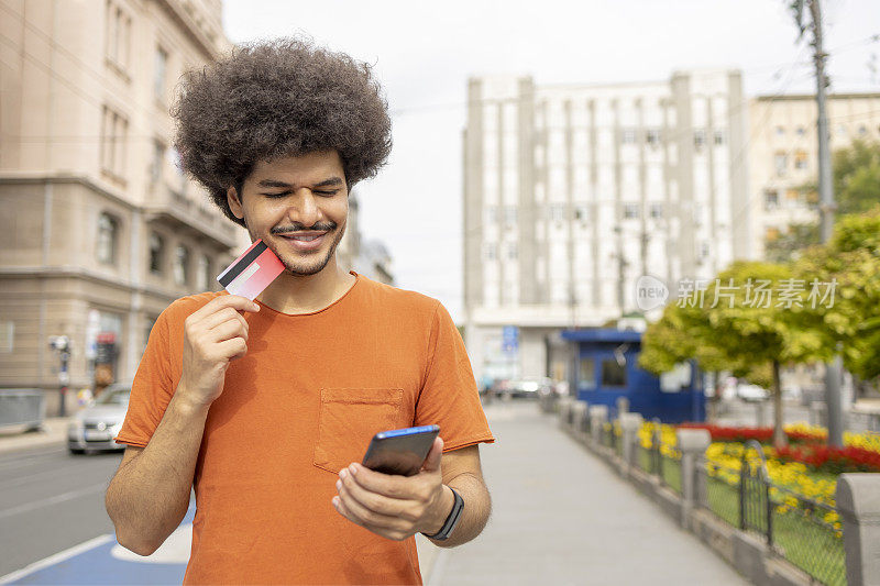 一名男子在使用信用卡和智能手机网购时微笑