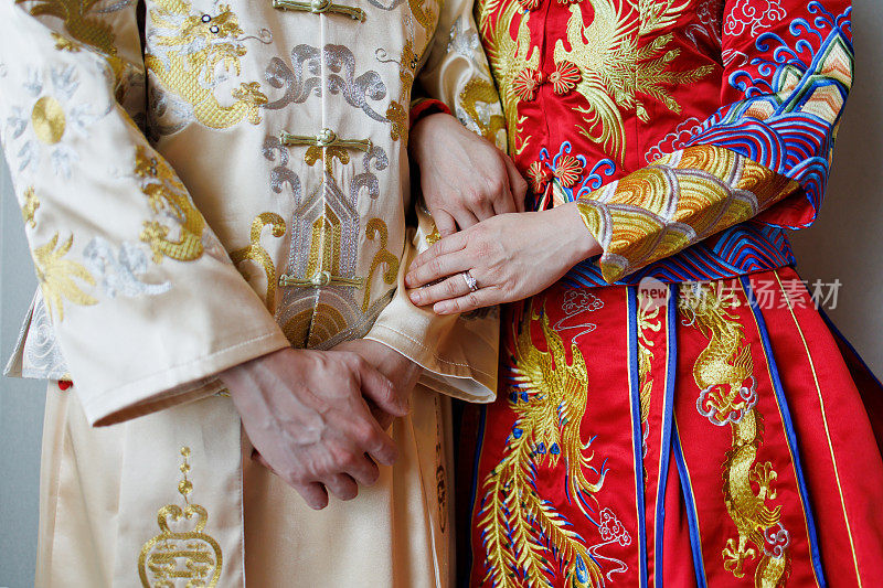 亚洲华人婚礼的新人手牵着手，穿着传统的中国服装。