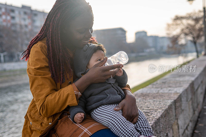 有爱心的年轻母亲正在给她的小宝宝喝水