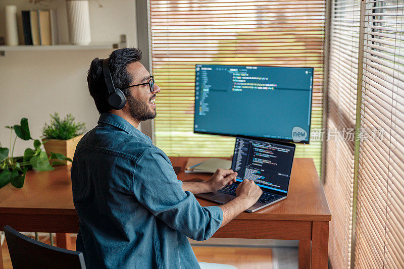 男性自由职业者制作新的项目作为网页设计师或程序员在他的电脑在家里办公室