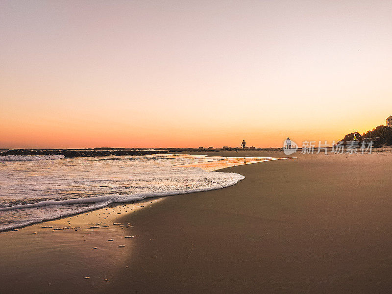 日落时分，岸边的海浪和身后的人的美丽风景