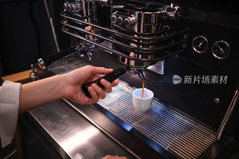 一名女服务员在自助餐厅的咖啡机上准备咖啡。
