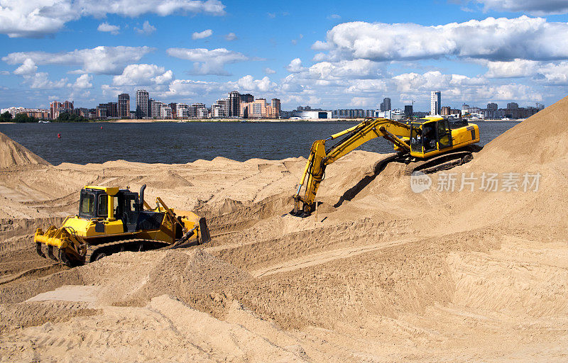城市河岸上的挖掘机挖着海滩上的沙子