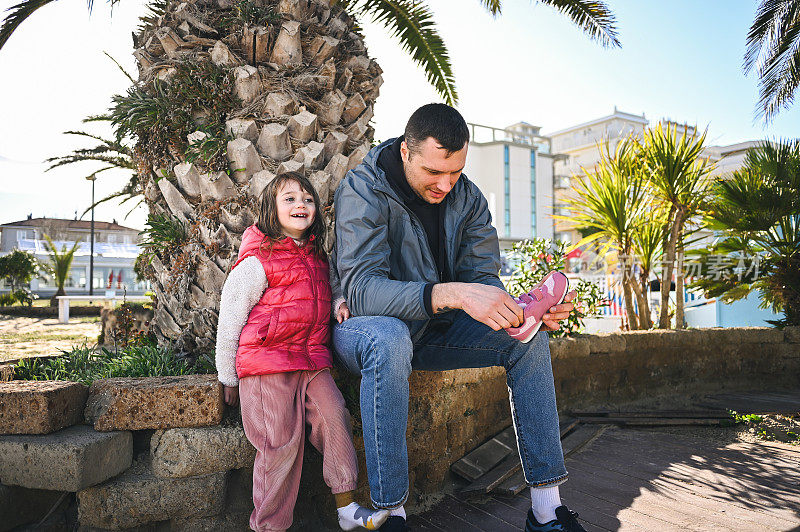 慈爱的父亲在公园帮小女孩穿鞋。