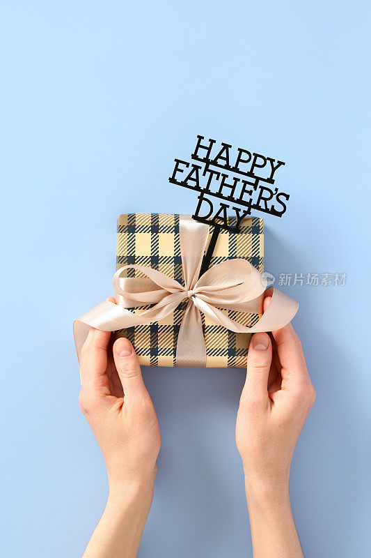 父亲节快乐的概念。女性手捧着复古的礼盒，用丝带包裹着蝴蝶结，上面写着父亲节快乐。