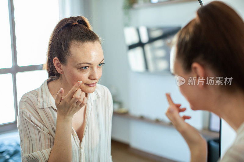 年轻女子在家里对着镜子化妆