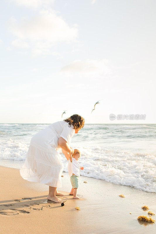 2023年春天，一位31岁的古巴裔美国母亲和她1岁的儿子在海滩岸线玩耍，在佛罗里达州棕榈滩的金色日出期间一起享受时光