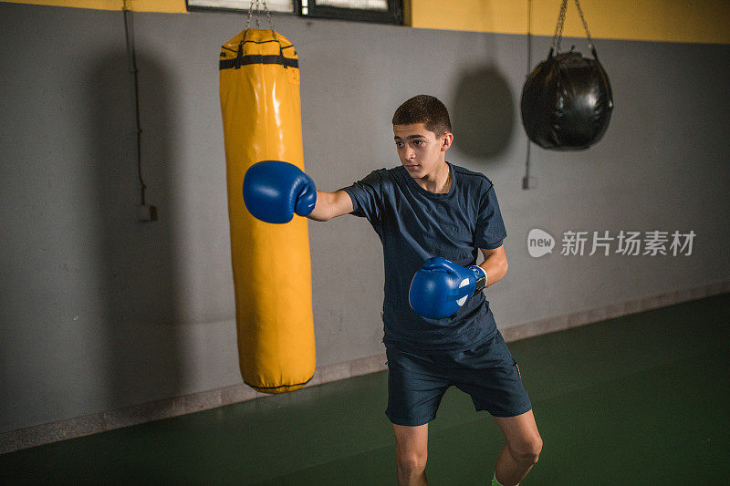 一个年轻的男性自由搏击运动员在拳击馆训练，专注于变得更强壮