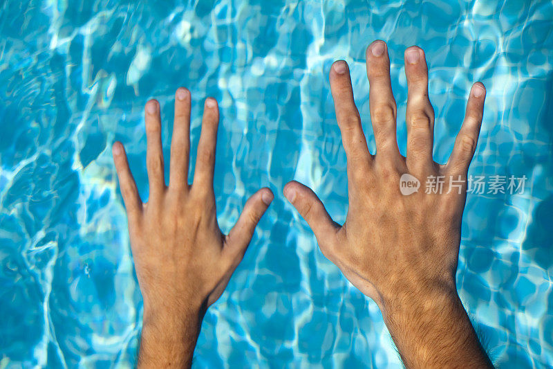 在游泳池水里张开双手。