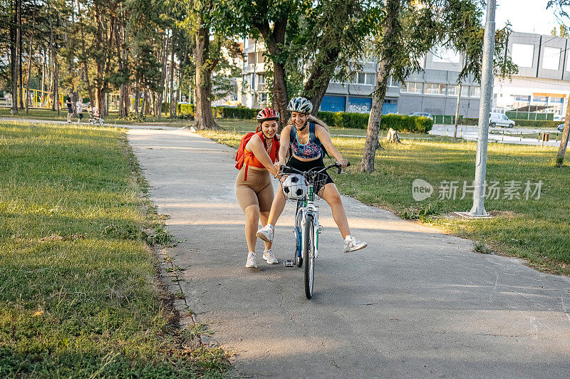 朋友们在城市公园里学习如何骑自行车