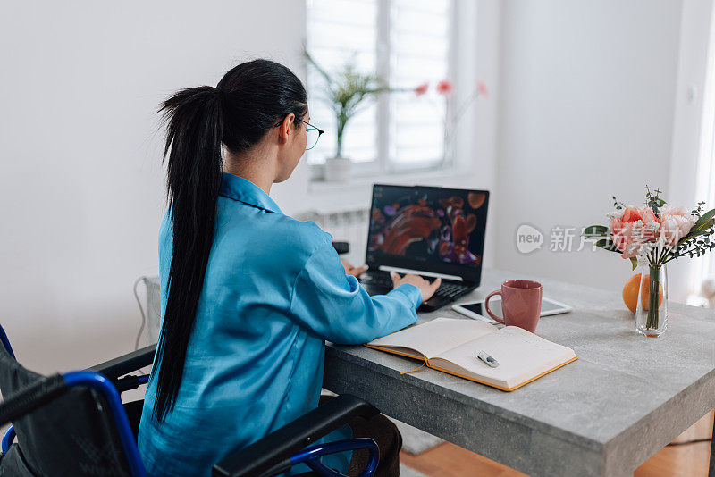 坐在轮椅上的年轻女子在远程办公环境中用笔记本电脑工作