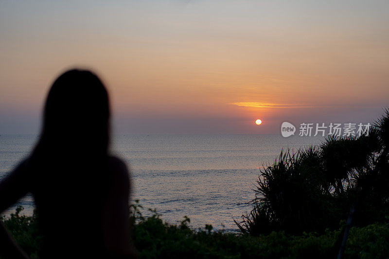 亚洲妇女在海洋地平线上欣赏日落日出的剪影