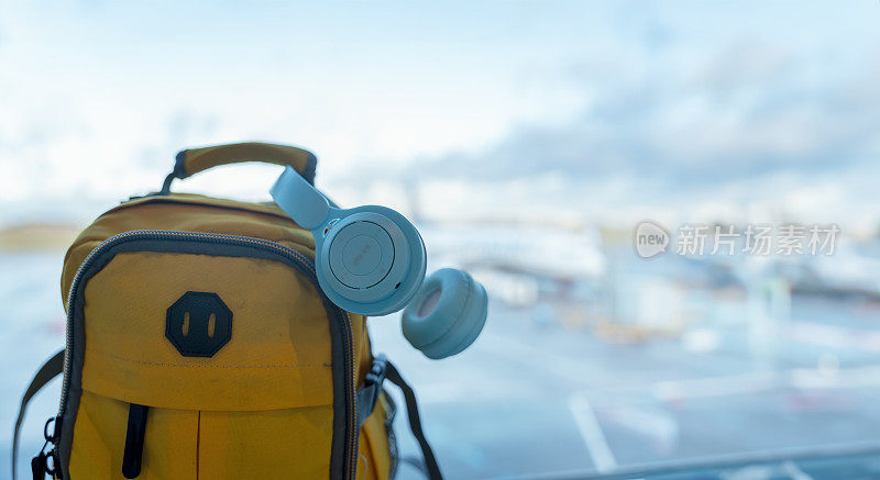 黄色背包和蓝色耳机在机场。旅行的概念。旅游旅游的概念。轻装旅行