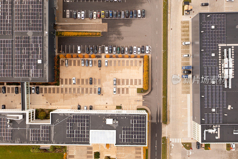 无人机拍摄的物流仓库，屋顶上有太阳能电池板，还有秋天早晨的汽车停车场