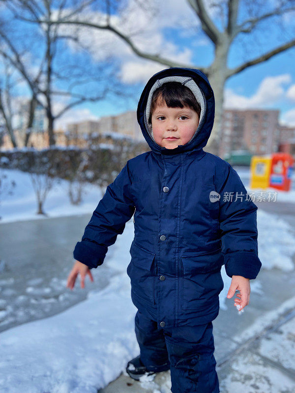 一个男孩站在公园的雪地里