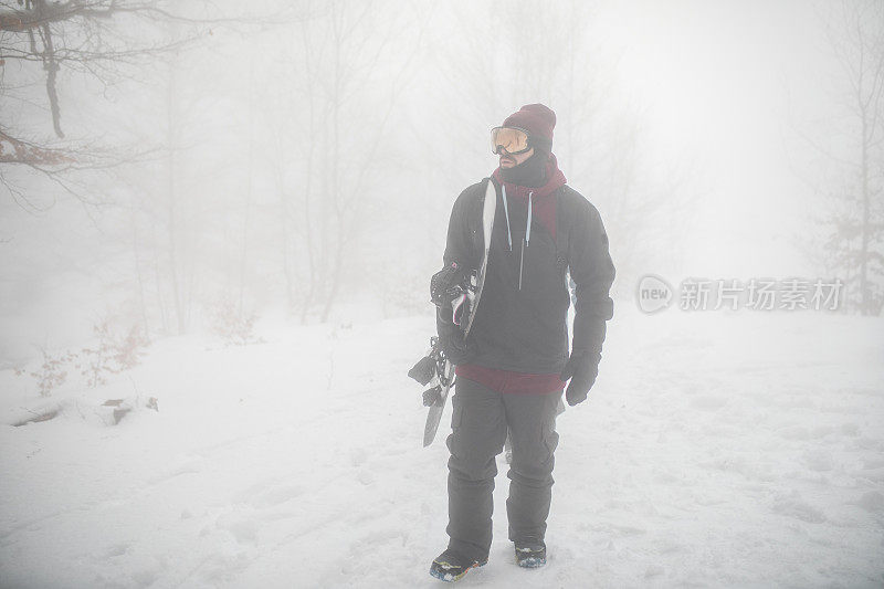 一个男性滑雪板运动员准备在一个雾蒙蒙的冬日骑滑雪板