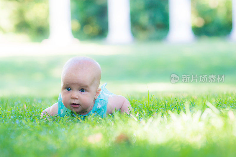 4个月大的孩子在草地上，背景是柱子