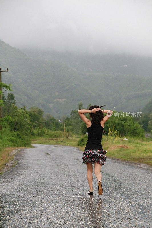 年轻的笑着女人在热带雨中奔跑。